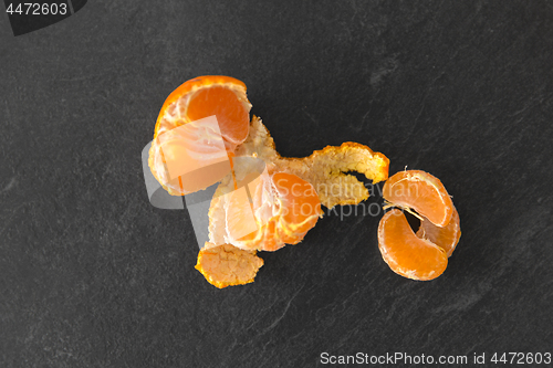 Image of close up of peeled mandarin on slate table top