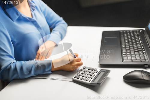 Image of businesswoman with papers working at night office