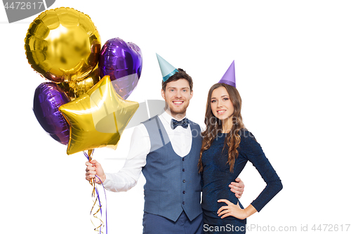 Image of happy couple with party caps and balloons