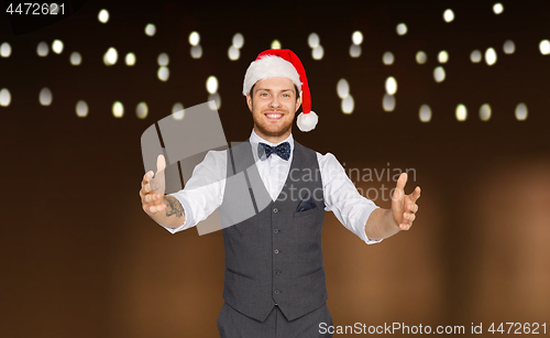 Image of happy man in santa hat holding something imaginary