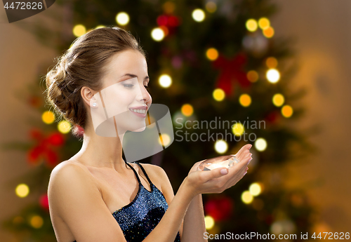 Image of woman holding big diamond over christmas tree