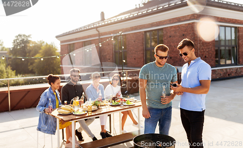 Image of happy friends having bbq party on rooftop