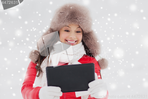 Image of woman in winter fur hat with tablet pc outdoors