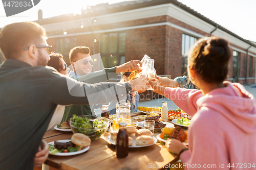 Image of happy friends toasting drinks at rooftop party