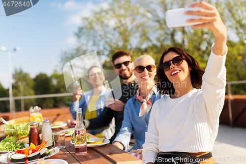 Image of happy friends taking selfie at rooftop party