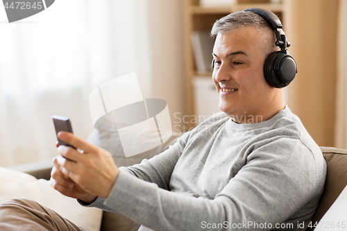Image of man with smartphone and headphones at home