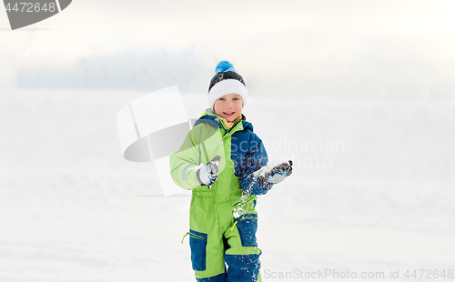 Image of happy little boy playing with snow in winter