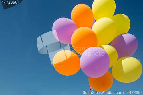 Image of close up of colorful helium balloons in blue sky