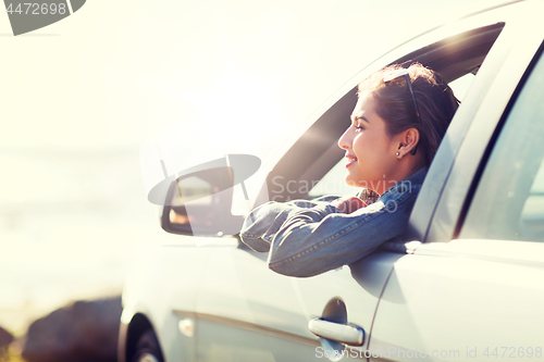 Image of happy teenage girl or young woman in car