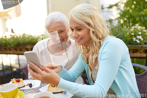 Image of daughter and senior mother with smartphone at cafe