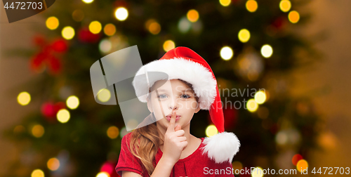 Image of girl in santa hat over christmas tree lights