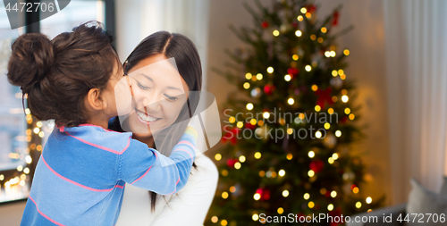 Image of happy daughter kissing her mother on christmas