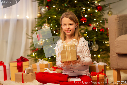 Image of smiling girl with christmas gift at home