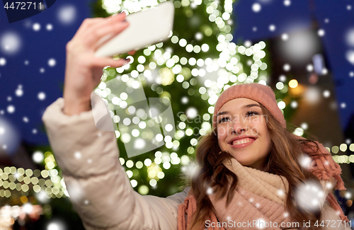 Image of young woman taking selfie over christmas tree