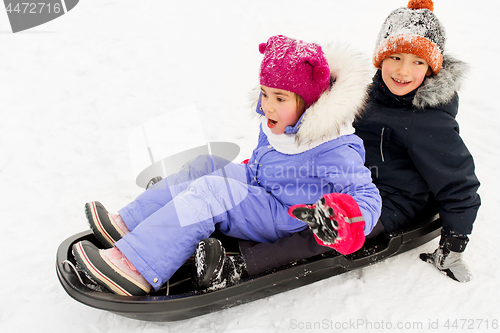 Image of little kids sliding on sled down hill in winter