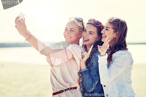 Image of group of smiling women taking selfie on beach