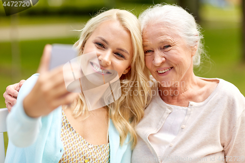 Image of daughter and senior mother taking selfie at park