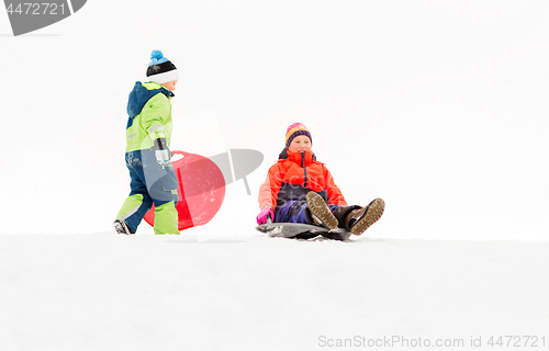 Image of happy kids sliding on sleds down hill in winter