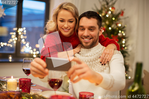 Image of happy couple taking selfie at christmas dinner