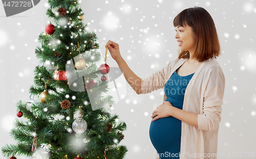 Image of pregnant woman decorating christmas tree at home