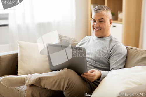 Image of man with laptop computer sitting on sofa at home