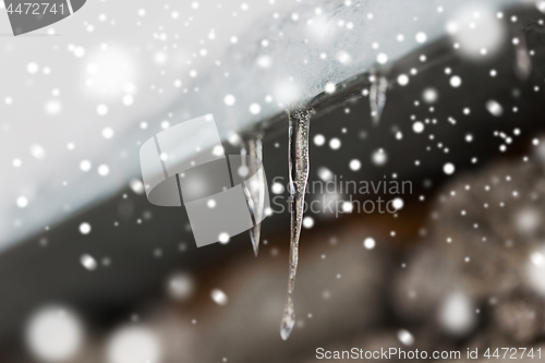 Image of icicles and snow hanging from building roof