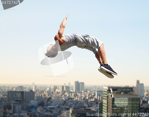 Image of man making parkour jumping over tokyo city