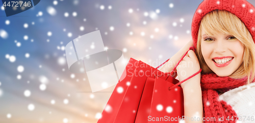 Image of woman with red shopping bags over snow background