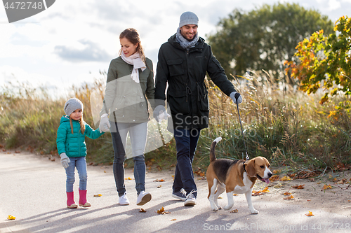 Image of happy family walking with beagle dog in autumn