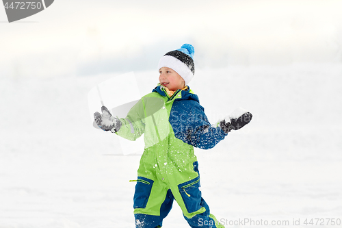 Image of happy boy playing and throwing snowball in winter