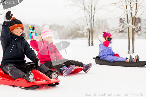 Image of happy little kids sliding on sleds in winter