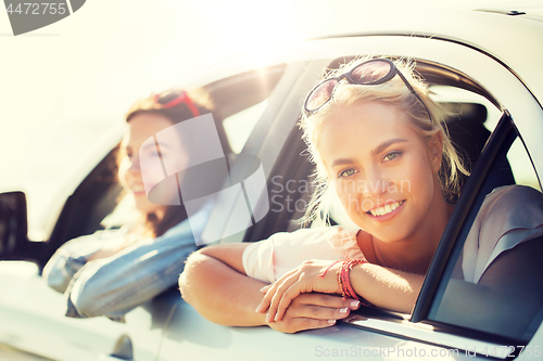 Image of happy teenage girls or women in car at seaside