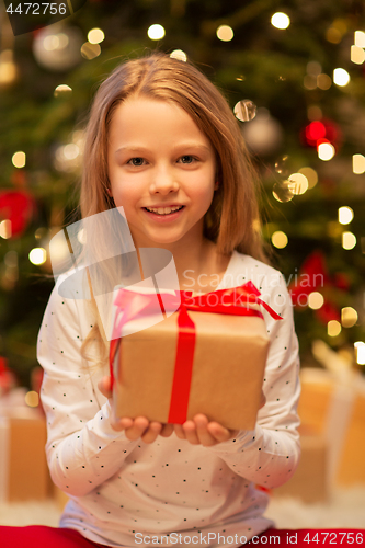 Image of smiling girl with christmas gift at home