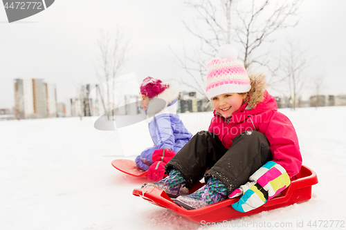 Image of happy little girls on sleds outdoors in winter