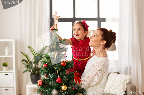 Image of mother and daughter decorating christmas tree