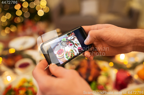 Image of hands photographing food at christmas dinner