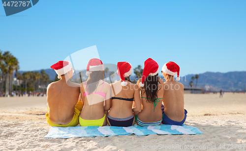 Image of friends in santa hats on venice beach on christmas