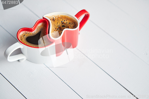 Image of Two heart shaped coffee cups conected with each other.