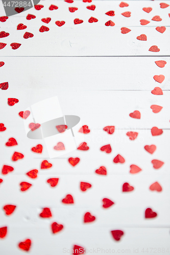 Image of Vlentine\'s Day composition. Heart shaped sequins placed on white wooden table