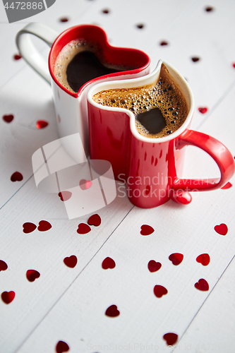 Image of Two heart shaped coffee cups conected with each other.