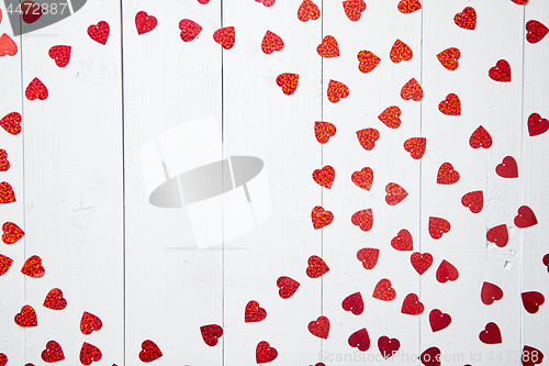 Image of Vlentine\'s Day composition. Heart shaped sequins placed on white wooden table