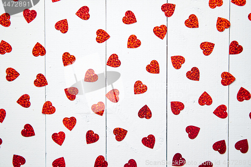 Image of Vlentine\'s Day composition. Heart shaped sequins placed on white wooden table