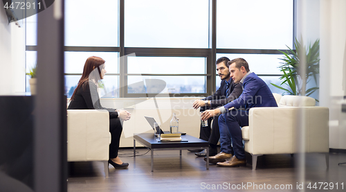 Image of Businessmen interviewing female candidate for job in modern corporate office.