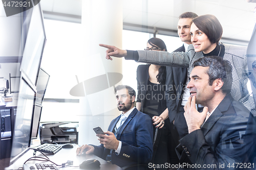 Image of Successful business team looking at trade data on computer screens in corporate office.