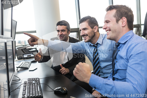 Image of Successful business team celebrates business success in modern corporate trading office.