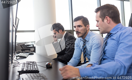 Image of Worried stock traders brainstorming in corporate office.