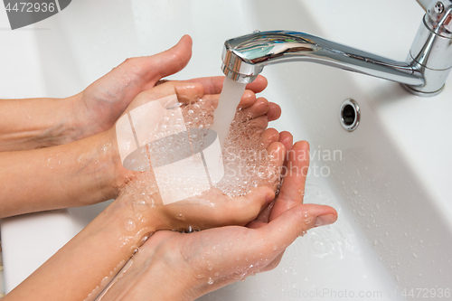 Image of Children\'s and adult hands take water flowing from the mixer in the palm
