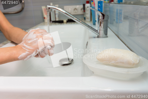 Image of The child carefully washes his hands with soap, in the foreground a bar of soap