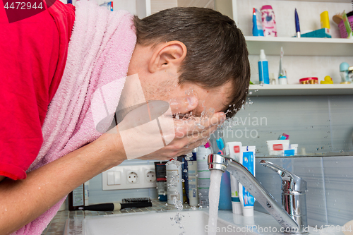 Image of Man washing his face in the morning in the bathroom