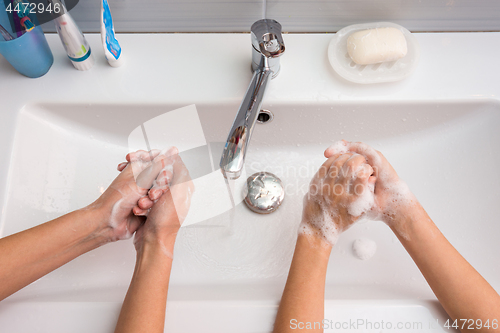 Image of Two people wash their hands in the sink, top view